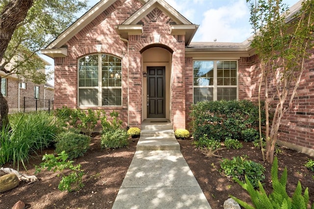 property entrance featuring brick siding and fence