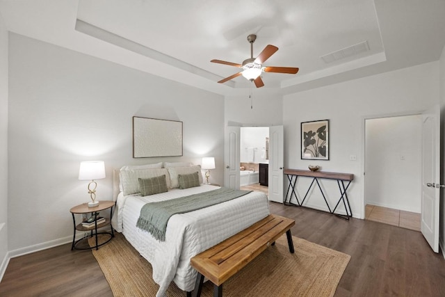 4924 Pyrenees Pass, Bee Cave, TX 78738 - bedroom featuring a tray ceiling, wood finished floors, ensuite bathroom, and a ceiling fan