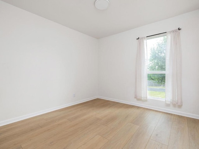 unfurnished room with light wood finished floors and baseboards