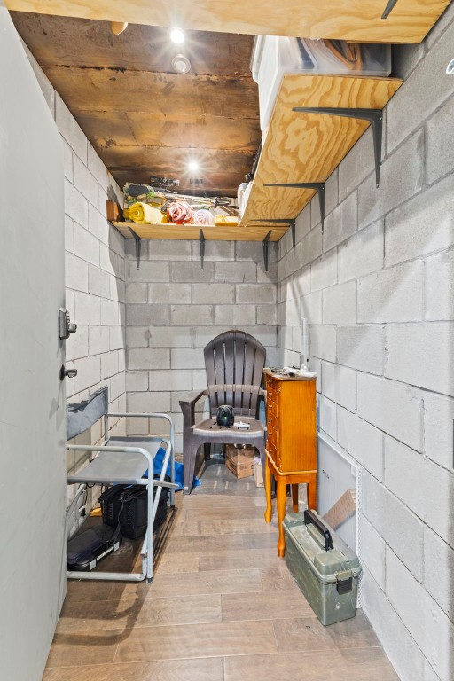 unfinished basement featuring hardwood / wood-style flooring and concrete block wall