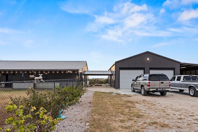 exterior space featuring fence, a garage, an outbuilding, and dirt driveway