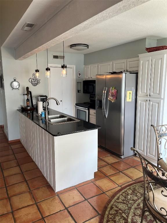 103 Island Dr Unit 8, Horseshoe Bay, TX 78657 - kitchen featuring stainless steel appliances, a sink, a peninsula, dark countertops, and white cabinetry