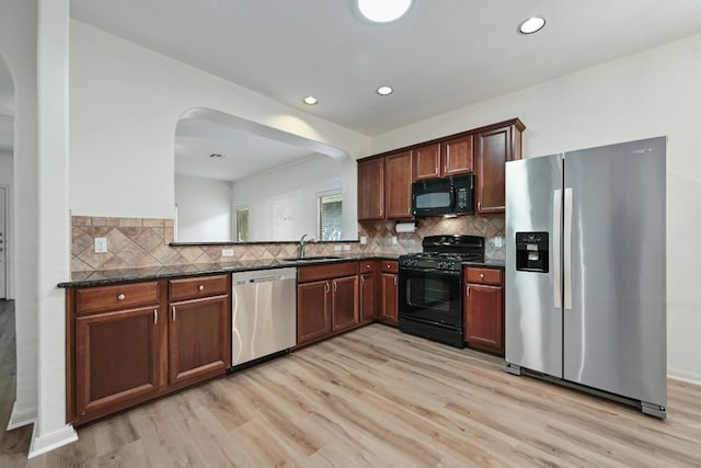 2408 Amur Dr, Austin, TX 78745 - kitchen with black appliances, arched walkways, light wood finished floors, and recessed lighting