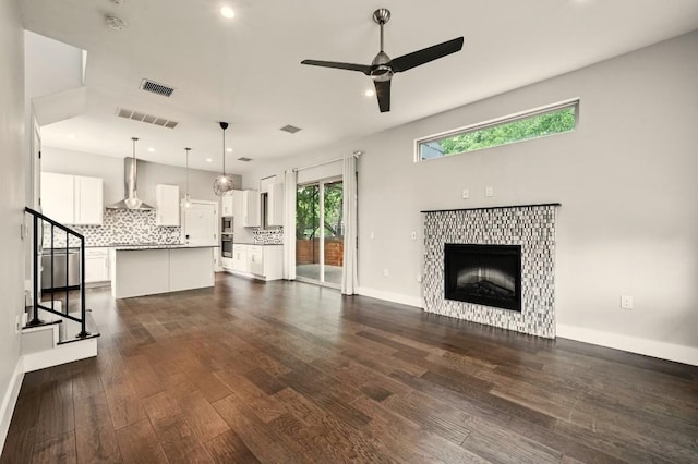 2305 E 16th St Unit A, Austin, TX 78702 - unfurnished living room featuring ceiling fan, recessed lighting, a tiled fireplace, stairway, and dark wood-type flooring