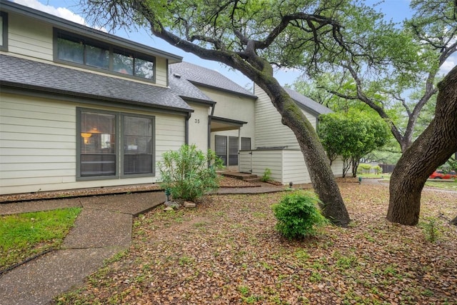 rear view of house with roof with shingles