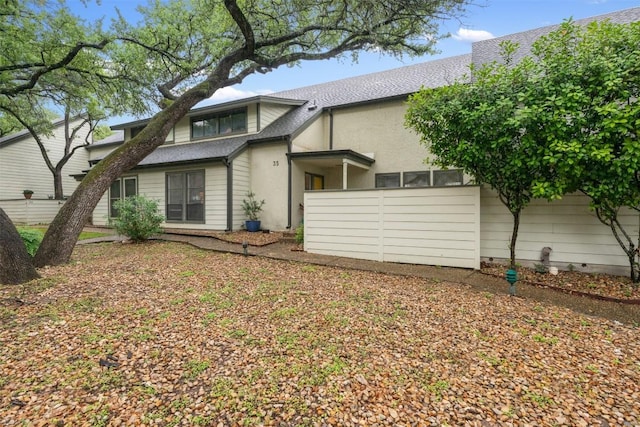 rear view of house with roof with shingles