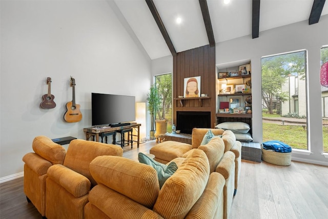 living area with beam ceiling, wood finished floors, high vaulted ceiling, baseboards, and a large fireplace