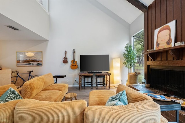 living room featuring high vaulted ceiling, wood finished floors, baseboards, and a large fireplace