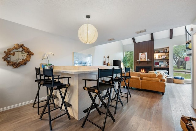 dining area featuring wood finished floors, a fireplace, and baseboards
