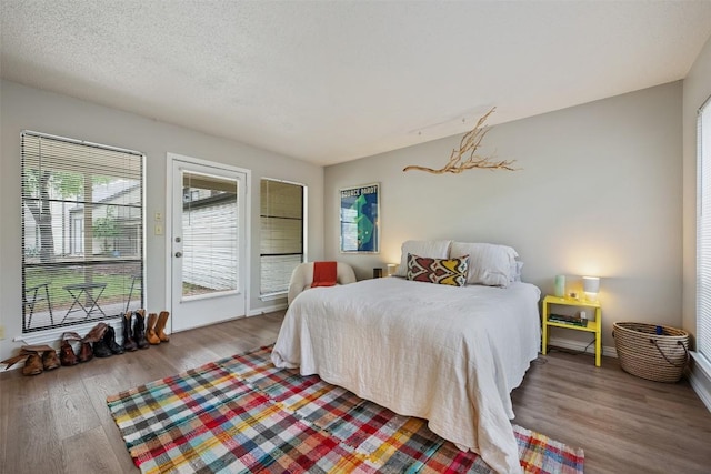 bedroom featuring access to outside, wood finished floors, and baseboards