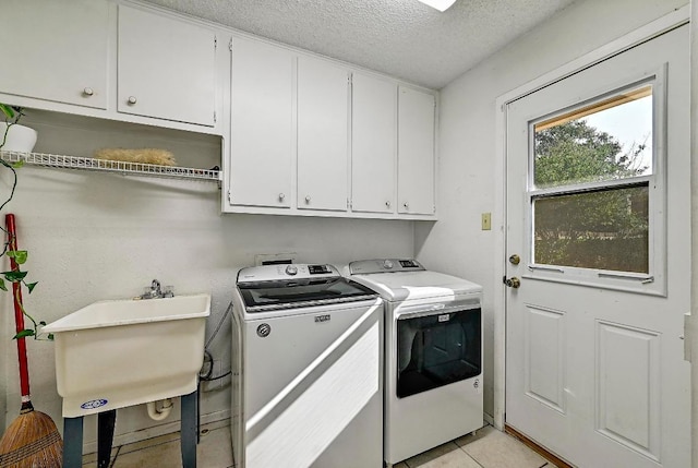11519 Shakespearean Way, Austin, TX 78759 - washroom with cabinet space, washing machine and clothes dryer, a textured ceiling, and light tile patterned flooring