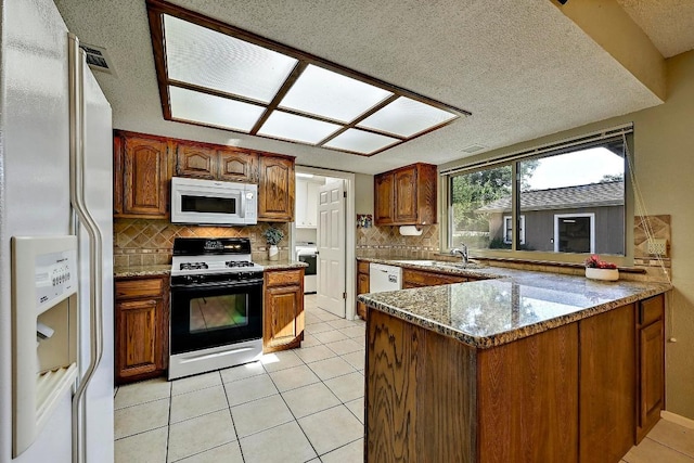 11519 Shakespearean Way, Austin, TX 78759 - kitchen featuring white appliances, light tile patterned floors, backsplash, a peninsula, and a textured ceiling