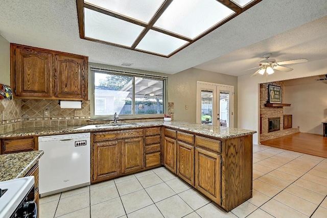11519 Shakespearean Way, Austin, TX 78759 - kitchen featuring dishwasher, a sink, a textured ceiling, a peninsula, and light tile patterned floors