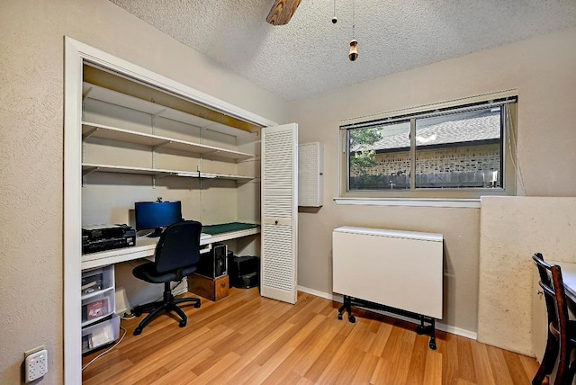 11519 Shakespearean Way, Austin, TX 78759 - office with wood finished floors, radiator heating unit, a textured ceiling, baseboards, and a ceiling fan