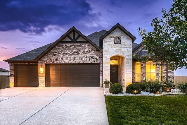 13417 Larrys Ln, Manchaca, TX 78652 - french country inspired facade featuring an attached garage, concrete driveway, stone siding, a front yard, and roof with shingles