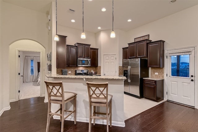 13417 Larrys Ln, Manchaca, TX 78652 - kitchen featuring appliances with stainless steel finishes, light wood-type flooring, dark brown cabinetry, arched walkways, and a peninsula