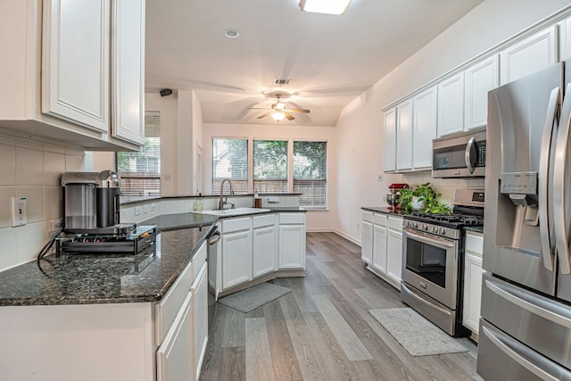 6419 Ira Ingram Dr, Austin, TX 78749 - kitchen featuring appliances with stainless steel finishes, a ceiling fan, a peninsula, light wood-style floors, and backsplash