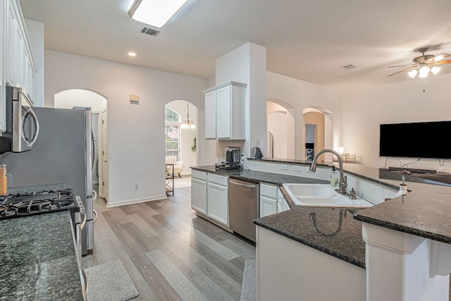6419 Ira Ingram Dr, Austin, TX 78749 - kitchen with appliances with stainless steel finishes, arched walkways, a ceiling fan, light wood-style flooring, and dark stone counters