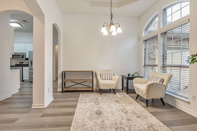 6419 Ira Ingram Dr, Austin, TX 78749 - living area featuring arched walkways, wood finished floors, a chandelier, and a tray ceiling