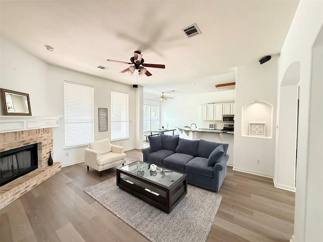6419 Ira Ingram Dr, Austin, TX 78749 - living area featuring ceiling fan, wood finished floors, a fireplace, and arched walkways