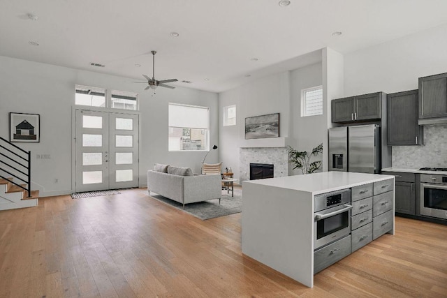 6116 Toscana Ave, Austin, TX 78724 - kitchen with stainless steel appliances, a glass covered fireplace, light countertops, ceiling fan, and light wood-type flooring