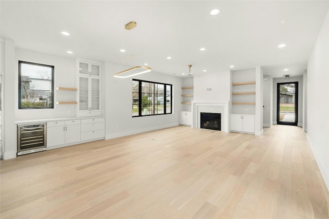 1719 Piedmont Ave, Austin, TX 78757 - unfurnished living room with beverage cooler, light wood-style floors, recessed lighting, a fireplace, and baseboards