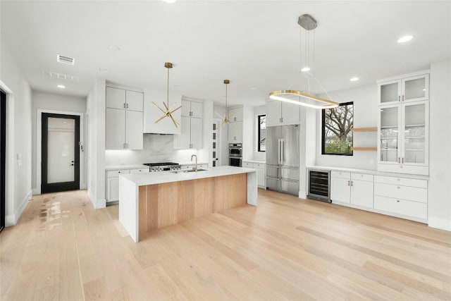 1719 Piedmont Ave, Austin, TX 78757 - kitchen featuring beverage cooler, appliances with stainless steel finishes, a sink, light countertops, and light wood-style flooring