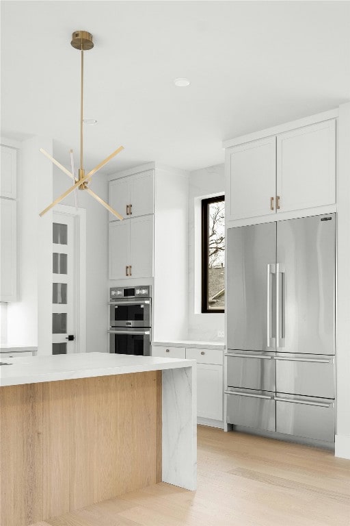 1719 Piedmont Ave, Austin, TX 78757 - kitchen with stainless steel appliances, light countertops, white cabinets, and light wood-type flooring