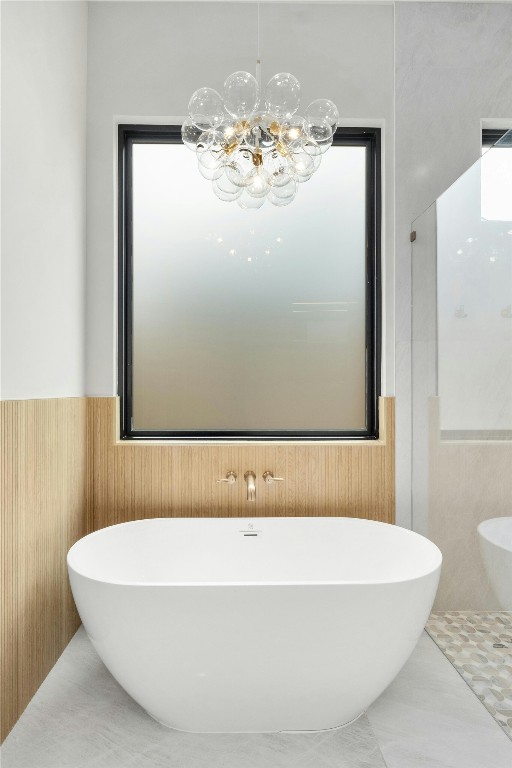 1719 Piedmont Ave, Austin, TX 78757 - bathroom with wainscoting, a soaking tub, a chandelier, and tile walls