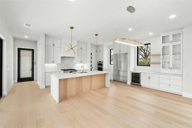 1719 Piedmont Ave, Austin, TX 78757 - kitchen featuring beverage cooler, stainless steel appliances, light wood finished floors, light countertops, and recessed lighting