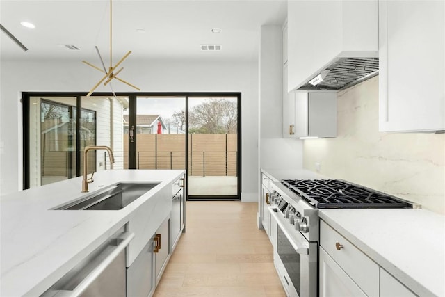 1719 Piedmont Ave, Austin, TX 78757 - kitchen featuring range with gas stovetop, custom exhaust hood, white cabinets, light wood-style floors, and recessed lighting