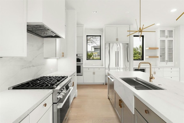 1719 Piedmont Ave, Austin, TX 78757 - kitchen with high quality appliances, ventilation hood, backsplash, light wood-style flooring, and white cabinetry