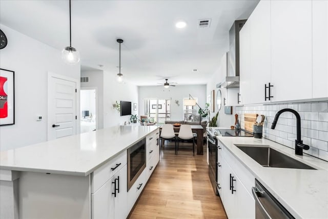 3101 Govalle Ave Unit 114, Austin, TX 78702 - kitchen with stainless steel appliances, a sink, wall chimney exhaust hood, backsplash, and a ceiling fan