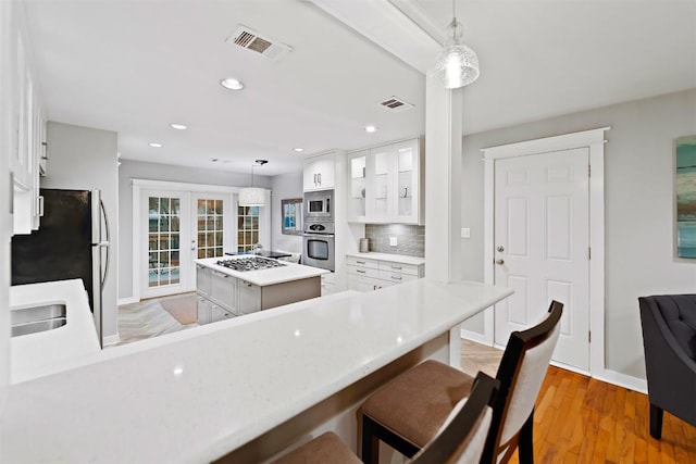 5614 Shoalwood Ave, Austin, TX 78756 - kitchen featuring appliances with stainless steel finishes, light countertops, white cabinets, baseboards, and light wood-style flooring