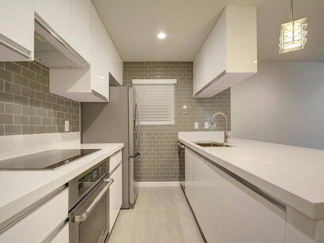 3110 Red River St Unit C-402, Austin, TX 78705 - kitchen with appliances with stainless steel finishes, a sink, white cabinetry, under cabinet range hood, and light countertops