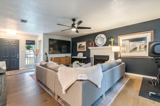 12005 Thompkins Dr, Austin, TX 78753 - living room with ceiling fan, a fireplace, wood finished floors, and a textured ceiling