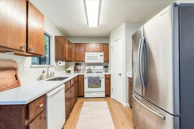 12005 Thompkins Dr, Austin, TX 78753 - kitchen with white appliances, light wood-style flooring, brown cabinetry, light countertops, and a textured ceiling