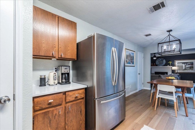 12005 Thompkins Dr, Austin, TX 78753 - kitchen with freestanding refrigerator, light wood-type flooring, a chandelier, brown cabinets, and light countertops