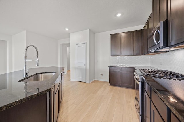 3747 Liberi Ln, Round Rock, TX 78665 - kitchen featuring stainless steel appliances, dark stone counters, light wood finished floors, dark brown cabinets, and decorative backsplash