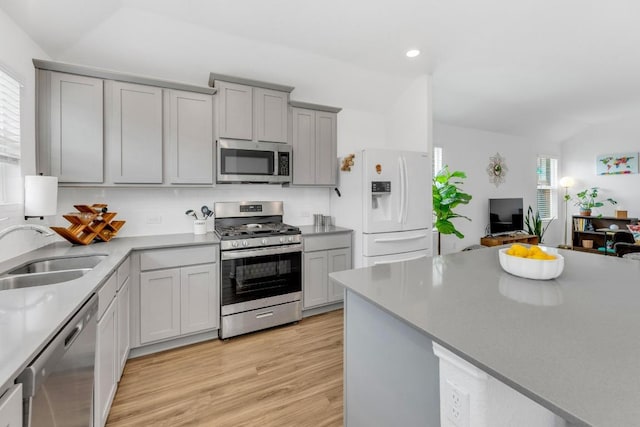 3201 Dusted Daisey St, Pflugerville, TX 78660 - kitchen featuring appliances with stainless steel finishes, gray cabinets, light wood-type flooring, recessed lighting, and vaulted ceiling