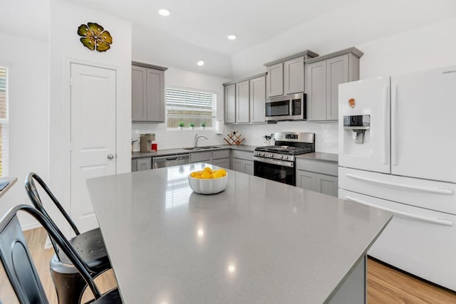 3201 Dusted Daisey St, Pflugerville, TX 78660 - kitchen featuring appliances with stainless steel finishes, gray cabinetry, a sink, a breakfast bar area, and tasteful backsplash