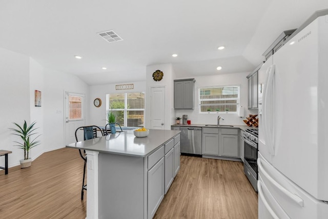 3201 Dusted Daisey St, Pflugerville, TX 78660 - kitchen featuring stainless steel appliances, gray cabinets, a breakfast bar area, light wood finished floors, and recessed lighting