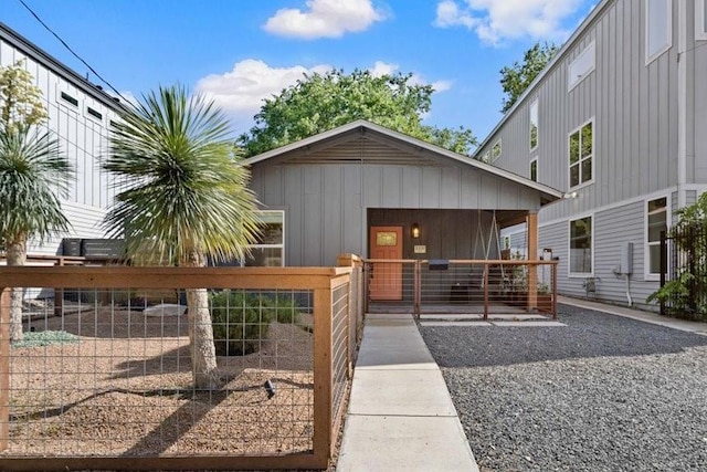 view of front of property featuring board and batten siding, a porch, and fence