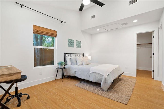 bedroom featuring light wood-type flooring, baseboards, a walk in closet, a ceiling fan, and high vaulted ceiling