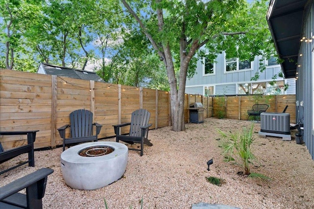fenced backyard with central AC unit and a fire pit