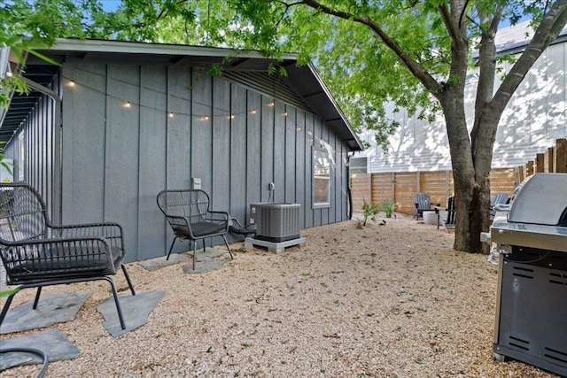 view of side of home with board and batten siding, fence, and central AC