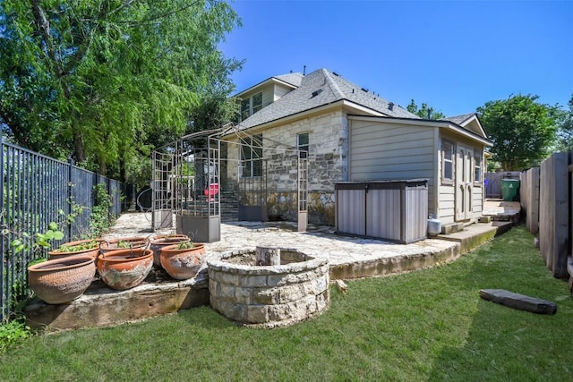 view of side of home featuring stone siding, a patio, and a shingled roof