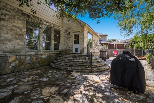 doorway to property featuring stone siding and fence