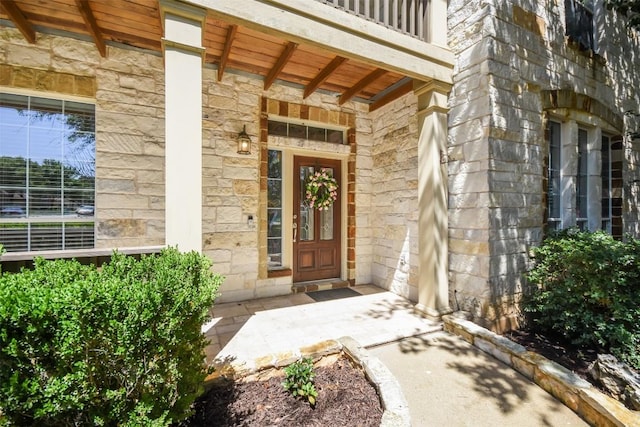 doorway to property with stone siding and covered porch