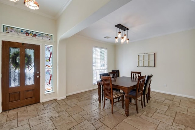 dining room featuring stone tile flooring, ornamental molding, a chandelier, and baseboards